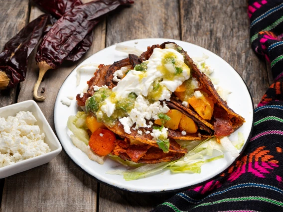Mexican red enchiladas with potato and pork chorizo also called Potosinas on wooden background
