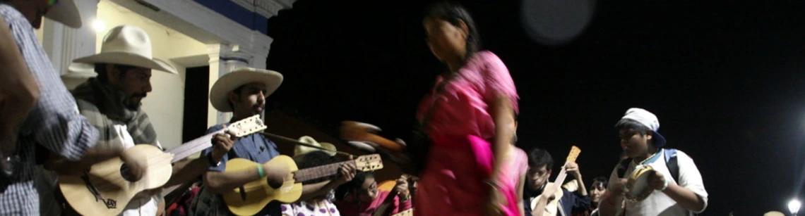 Group dancing son jarocho in public square at night