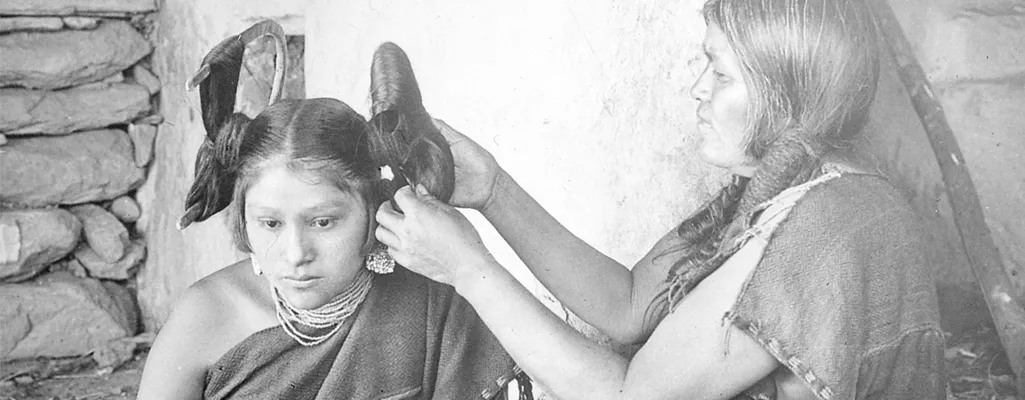 Hopi woman dressing hair of maiden (1900)