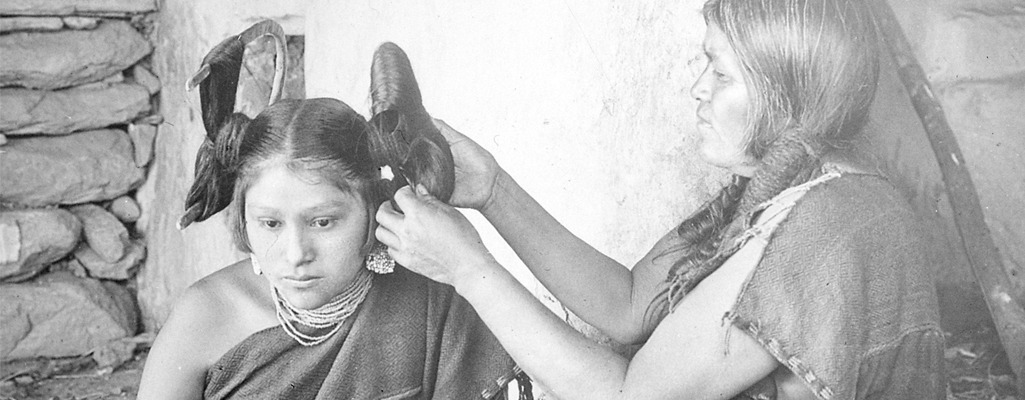 Hopi woman dressing hair of maiden (1900)
